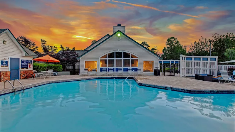  A sparkling pool with a clubhouse in the background at sunset.