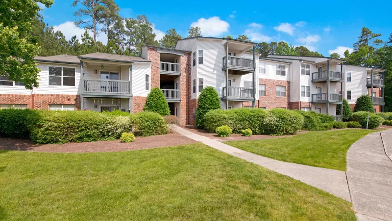 A lush green lawn leading to residential apartment buildings.