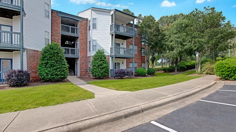 A driveway view with adjacent apartment buildings and well-maintained landscaping.