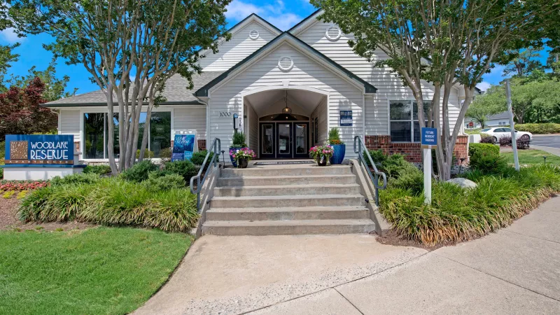 The front entrance of Woodlake Reserve Apartments with a welcoming sign and well-kept landscaping.