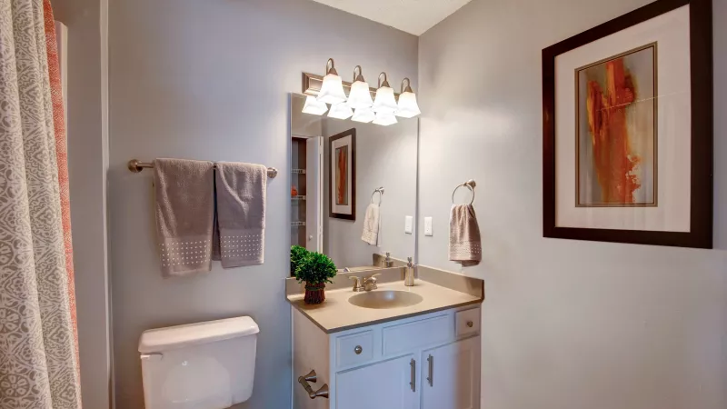 A clean and modern bathroom with a white vanity, large mirror, and soft lighting above.