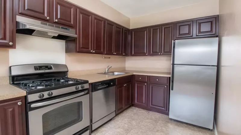A modern kitchen with dark wood cabinets, stainless steel appliances, and light tile flooring, creating a sleek and functional space.