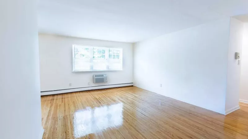 A bright, open living area with hardwood floors, large windows, and a ceiling fan, offering a comfortable and versatile space.