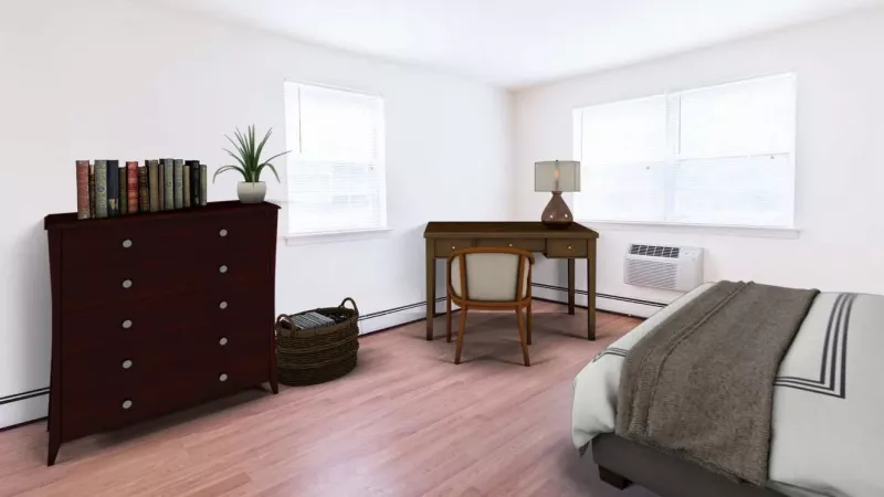 A bright bedroom with wood-look flooring, white walls, and large windows, creating a simple and clean aesthetic.