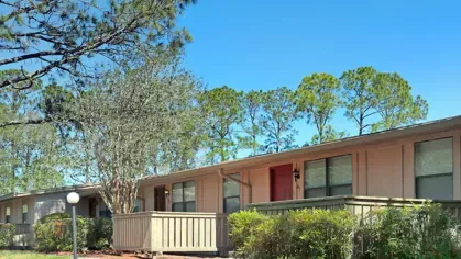 Image 3: A well-maintained apartment complex with trees and shrubs, offering a serene atmosphere with easy access to the building.
