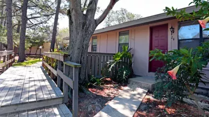Image 4: A front view of an apartment unit with a red door, walkways, and landscaped garden areas, providing a peaceful living environment.