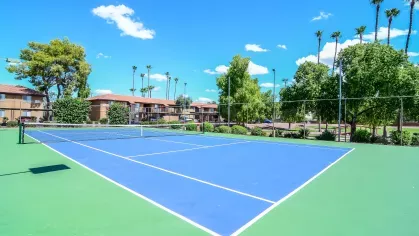 A well-maintained tennis court surrounded by green landscaping, offering recreational opportunities for residents at 505 West apartments.