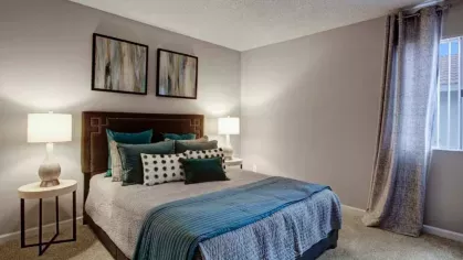A cozy bedroom featuring chic decor, textured bedding, and large windows with natural light, offering a comfortable and modern living space at 505 West Apartments.
