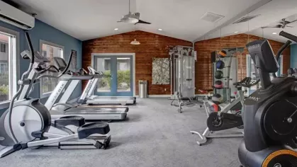 A modern fitness center at 505 West Apartments, equipped with treadmills, weight machines, and free weights, with ample natural light and a contemporary design.