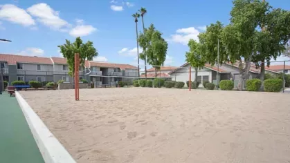 A spacious sand volleyball court at 505 West Apartments, surrounded by manicured greenery and offering a fun outdoor activity for residents.
