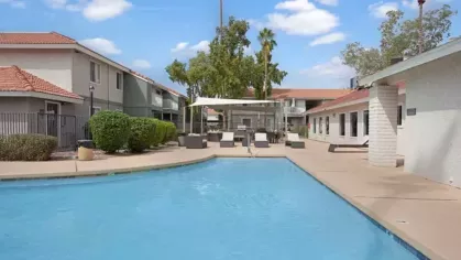 A sparkling swimming pool surrounded by lounge chairs, umbrellas, and lush landscaping, offering a relaxing retreat for residents at 505 West apartments.