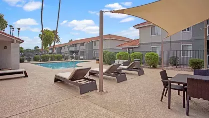 A sparkling swimming pool surrounded by lounge chairs, umbrellas, and lush landscaping, offering a relaxing retreat for residents at 505 West apartments.