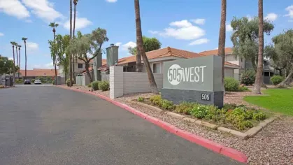 The 505 West Apartments community entrance sign surrounded by well-maintained landscaping and tall palm trees, creating a welcoming first impression.