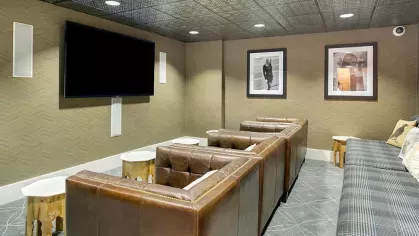 Cozy media room with leather seating, a large TV, and decorative wall accents.
