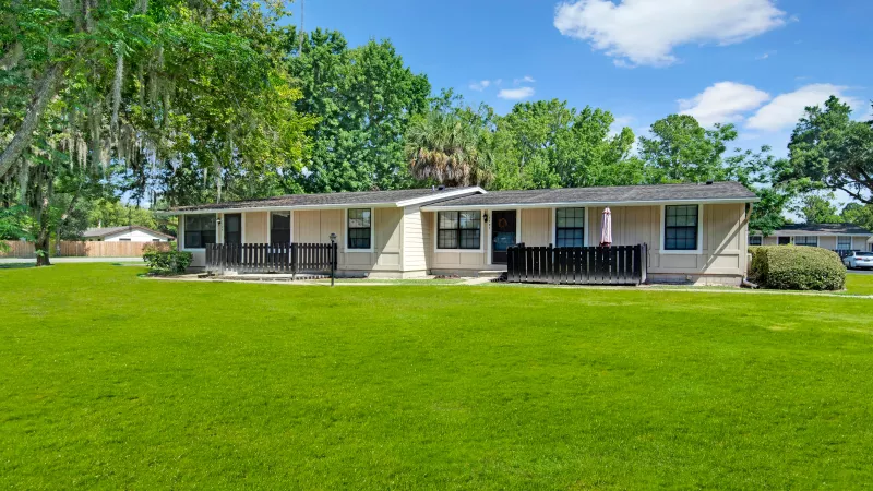 A wide grassy courtyard with single-story homes bordered by wooden fences.