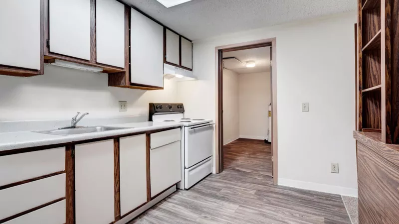 Spacious kitchen layout at Bridgepoint Apartments with a view into the laundry room and open shelving.