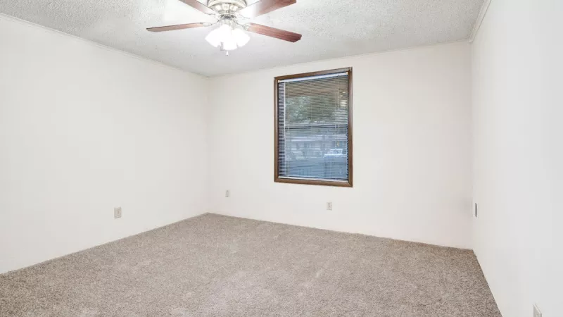 Cozy bedroom in Bridgepoint Apartments featuring a ceiling fan, neutral carpeting, and a spacious closet.