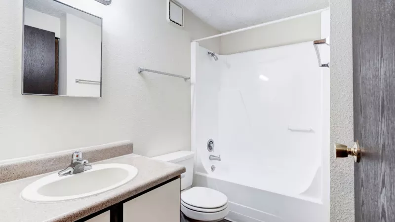 Clean bathroom design at Bridgepoint Apartments with a large mirror, sink vanity, and a shower-tub combination.