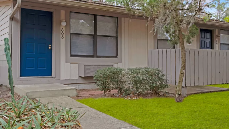 Charming single-story apartment buildings with vibrant landscaping, bright blue doors, and private entrances, reflecting the inviting and well-maintained community of Bridgepoint Apartments.