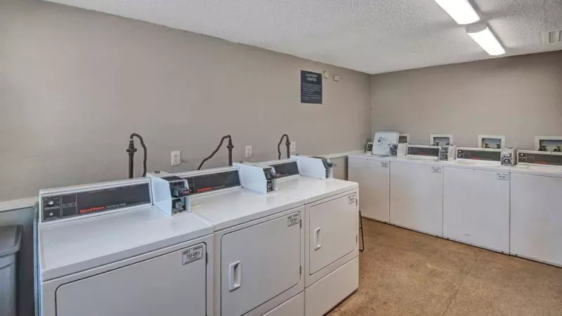 A clean and well-lit laundry room equipped with multiple washers and dryers for resident use. This image highlights the convenient on-site laundry facilities at Broadview Oaks Apartments.