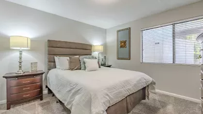 A comfortable bedroom with a plush bed, bedside lamps, and soft carpet flooring.