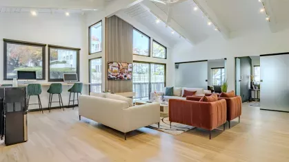 Spacious community lounge at Chatsworth Apartments with stylish seating, high ceilings, and a computer station for residents.