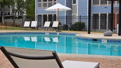 Refreshing poolside at Chatsworth Apartments with sun loungers and scenic views of the property.
