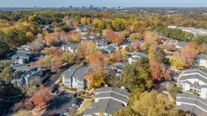 An aerial view of Chatsworth Apartments in Chamblee, GA, showcasing a serene community surrounded by vibrant autumn foliage and lush greenery.