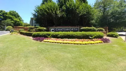 Beautifully landscaped entrance to Chatsworth Apartments, featuring a manicured lawn, colorful flowers, and the community's welcoming signage.
