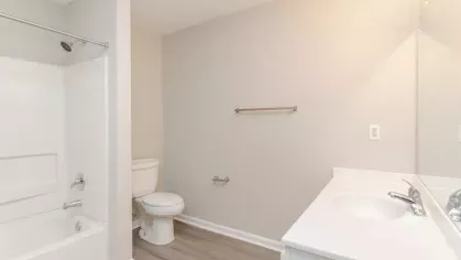 A modern bathroom featuring a shower-tub combination, a single vanity with a large mirror, and neutral finishes.