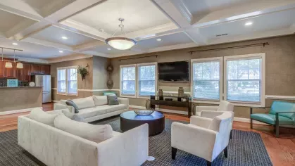 Elegant community lounge with cozy seating, flat-screen TVs, and a kitchenette for resident gatherings or relaxation.