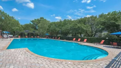 Large resort-style pool with lounge chairs and shaded seating, ideal for relaxation or social gatherings.