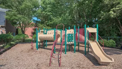 Playground at Maple Bay Apartments with colorful slides and climbing structures, surrounded by lush greenery for a family-friendly environment.