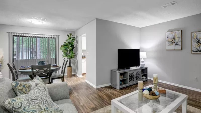 Spacious living room with modern decor, a flat-screen TV, and ample natural light at Norcross Crossings Apartments.