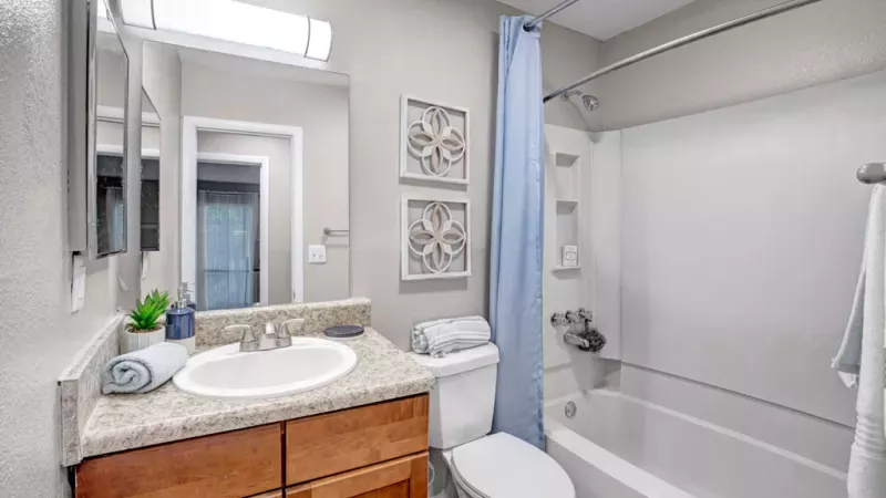 Updated bathroom with a modern vanity, full-size tub, and decorative wall art.