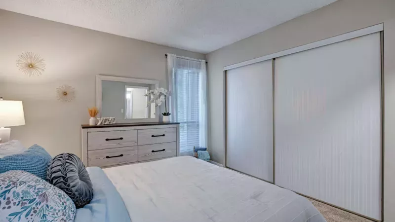 Elegant bedroom at Norcross Crossings Apartments with cozy bedding, soft lighting, and large windows for natural light and comfort.