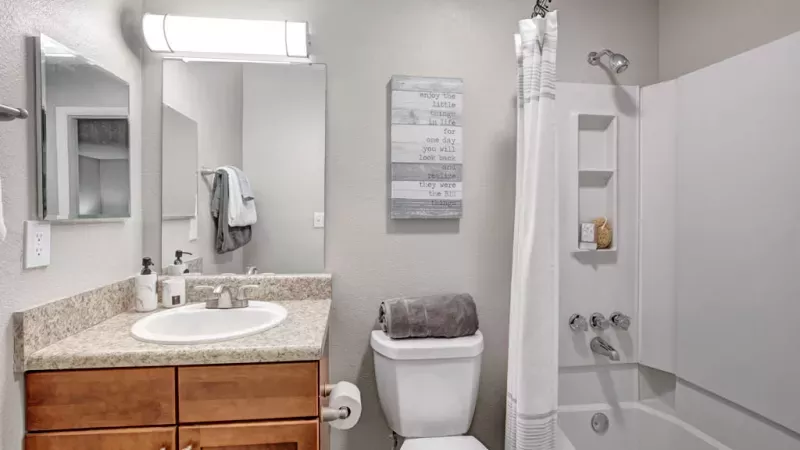Modern bathroom design at Norcross Crossings Apartments, highlighting a sleek vanity, large mirror, and clean shower area for a relaxing experience.