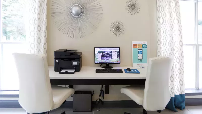 A modern business center at Norcross Crossings Apartments with a computer and printer, ideal for residents' remote work or study needs.