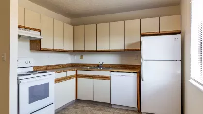 A fully equipped kitchen featuring white appliances, spacious cabinetry, and a tiled floor, offering a perfect space for meal preparation and gatherings.