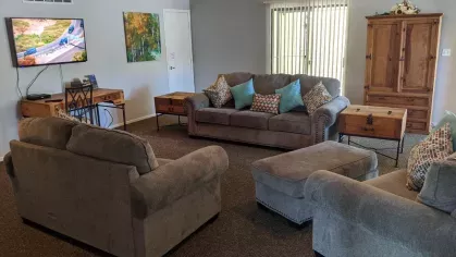 A cozy clubhouse with comfortable sofas, a dining area, and a mounted TV, creating an inviting space for residents to gather and relax