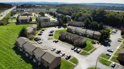 An aerial view showcasing the layout of North River Place Apartments, surrounded by lush green lawns and ample parking spaces