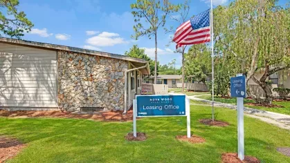The Nova Wood Apartments leasing office featuring a stone exterior and an American flag in front.