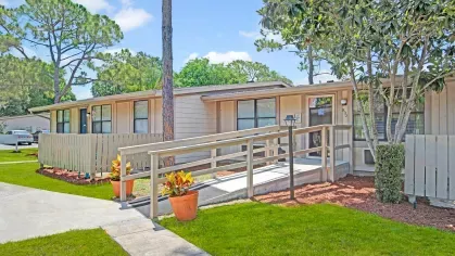 A close-up view of an accessible ramp leading to an apartment entrance adorned with decorative plants.