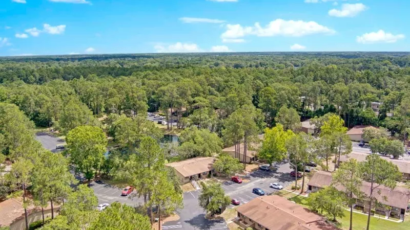 An aerial view of an apartment community nestled in a lush, wooded area.