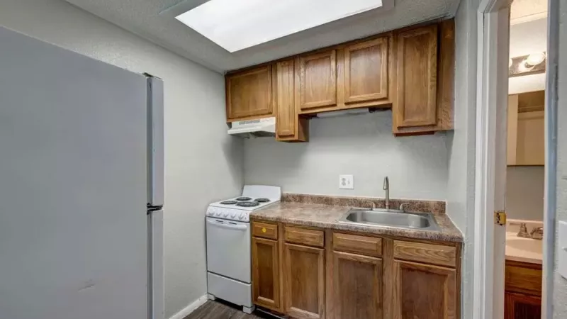 Another view of the kitchen highlighting the countertop, sink, and adjacent bathroom entry.