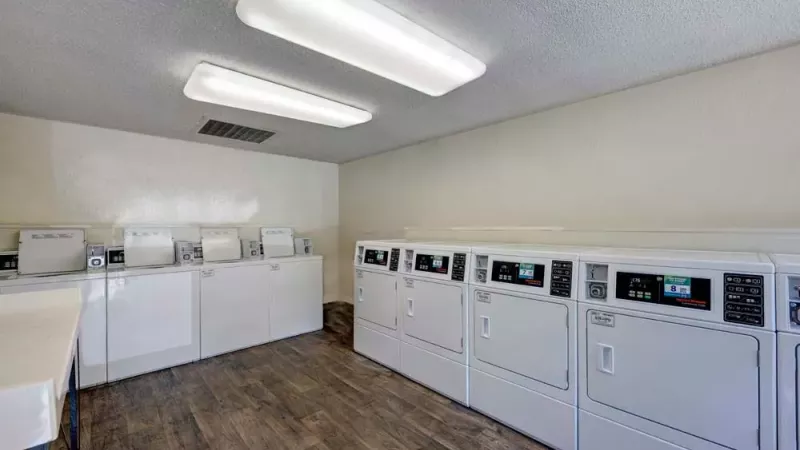 A laundry room equipped with modern washing machines and dryers, along with folding tables.