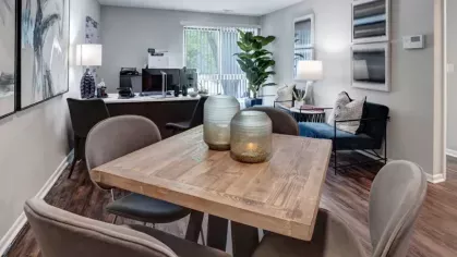 Stylish leasing office with a wooden dining table, contemporary chairs, and decorative accents.