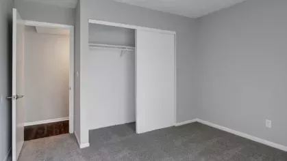 Bedroom with carpet flooring, neutral walls, and a built-in closet with sliding doors.