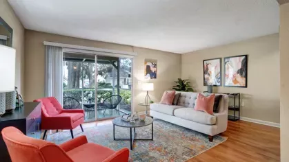 A cozy living room with a sofa, two armchairs, and large sliding glass doors leading to a patio.