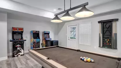 A game room with a pool table and vintage arcade machines.